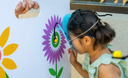 child with a butterfly mask participating in a game held during the pollinator event
