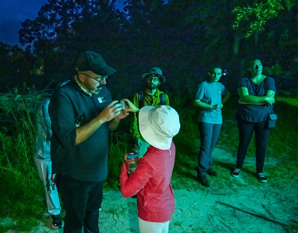 Vaughn Shirey speaks with young participant who has caught an insect during the nocturnal neighbors collecting event.