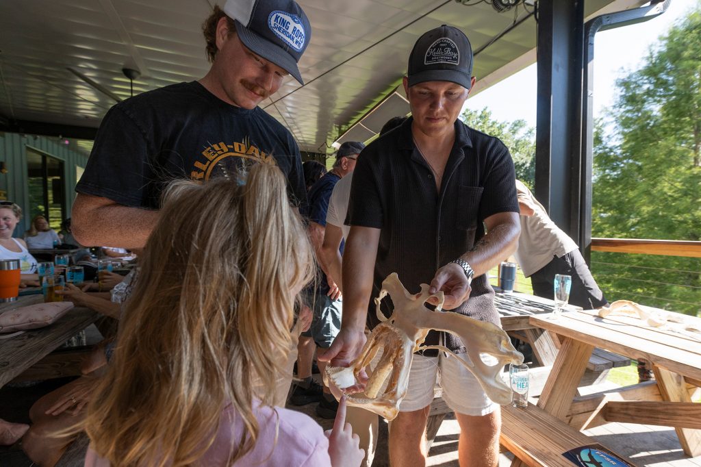 Joe Miguez holds a shark head skeleton while a girl touches the shark teeth