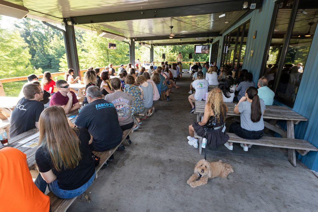 Large group of people sitting at picnic tables on the patio of the brewery
