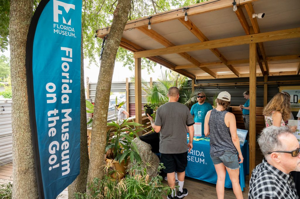 The Museum education team with the 'Florida Museum on the Go' sign speaking with people at Pollinator Palooza