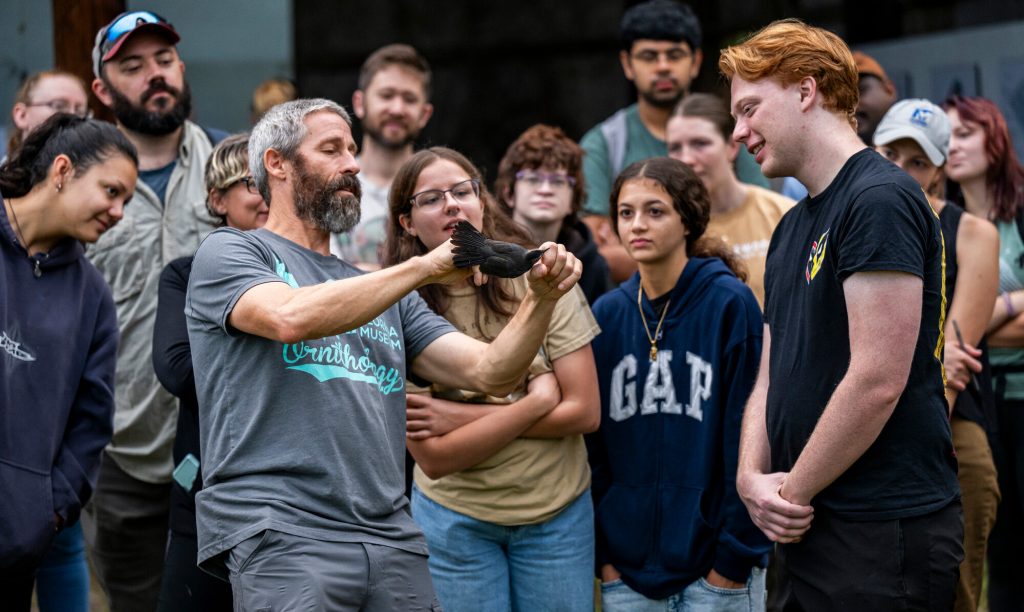 researcher holding a captured bird and speaking event participants