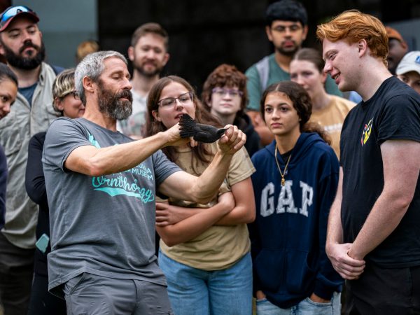 researcher holding a captured bird and speaking event participants