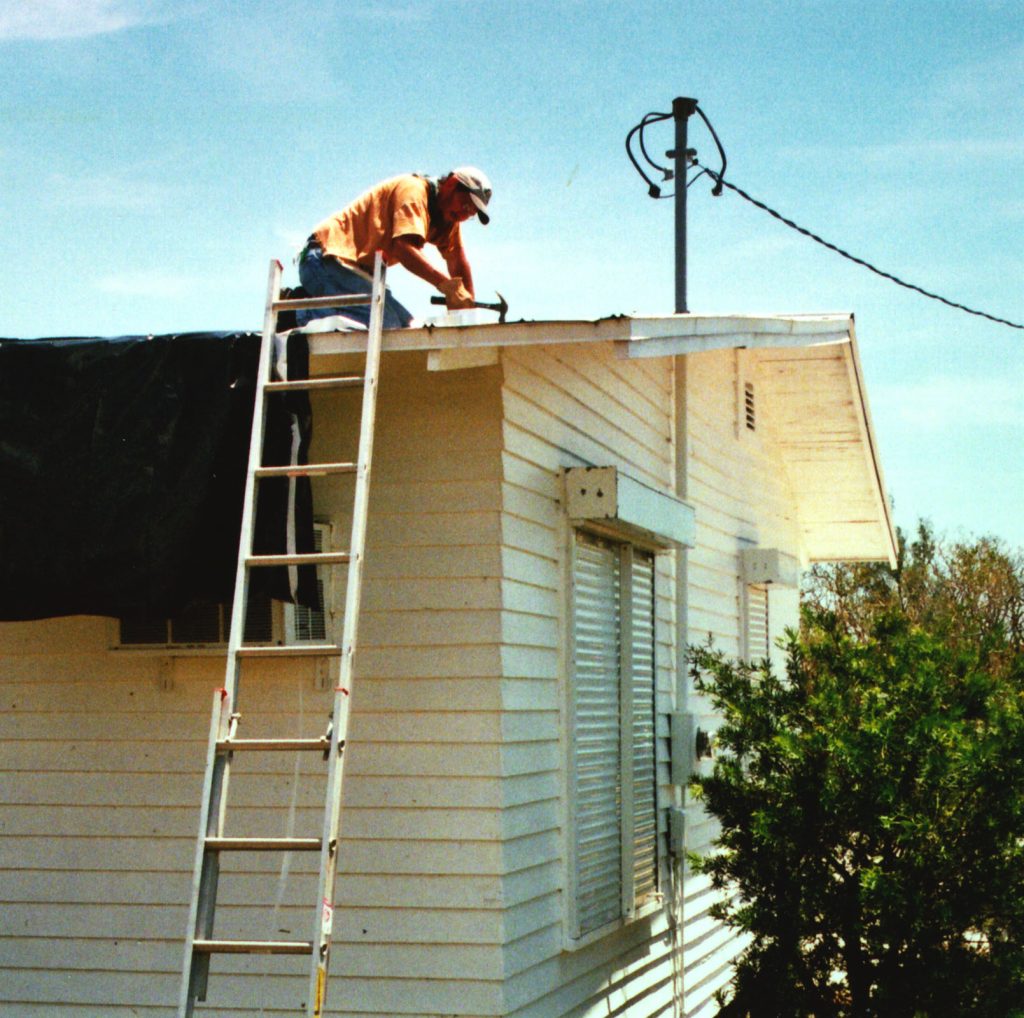 person on roof next to a ladder
