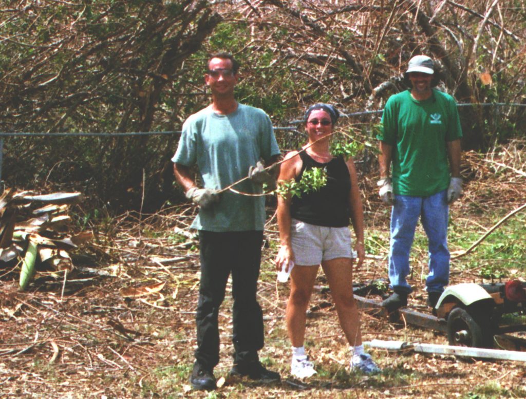 three people picking up hurricane debris