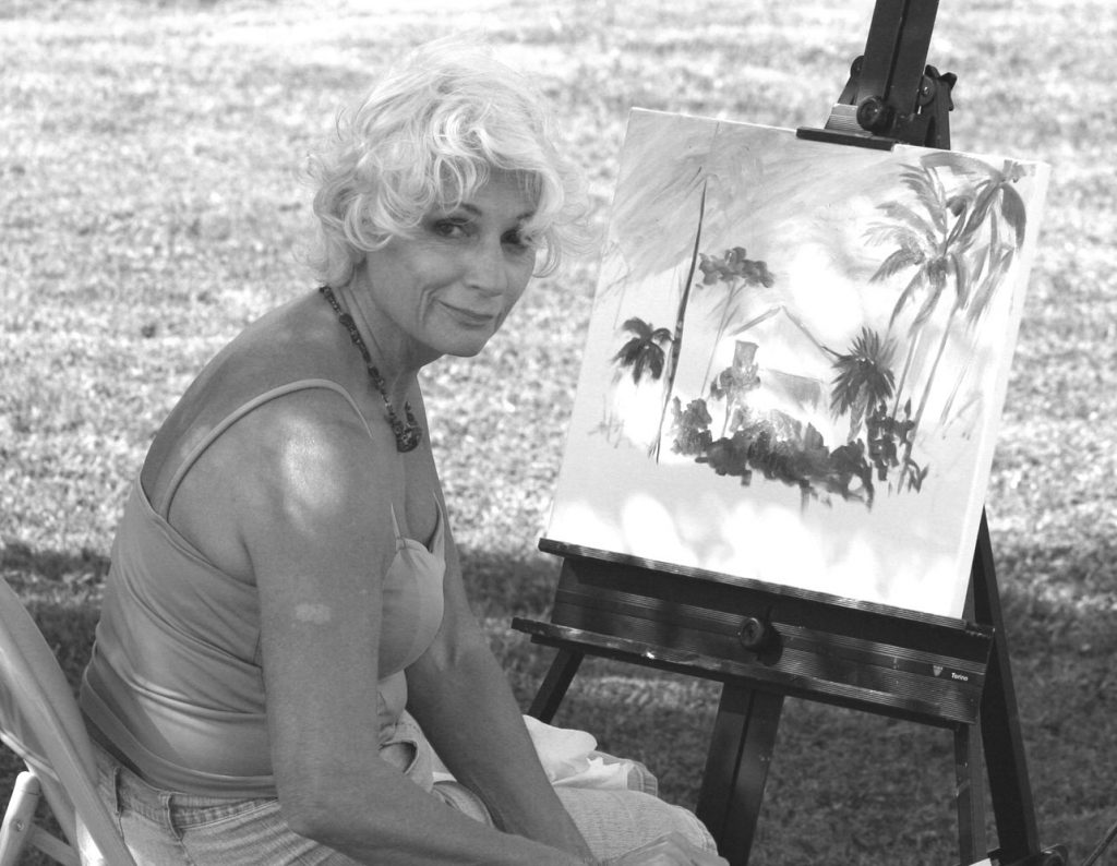 artist sitting next to her painting