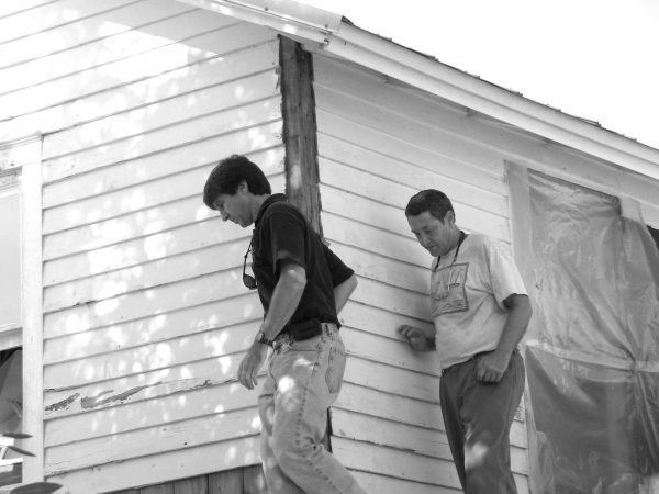 two to people walk carefully along the roof of a house