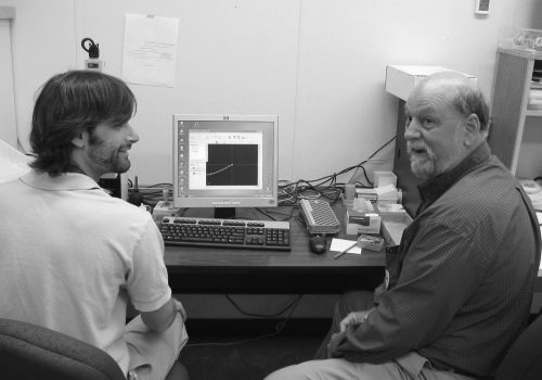 two researchers sit in front of a computer