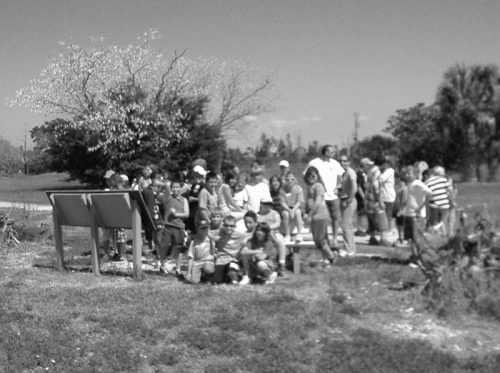 large group of children standing in front of display sign