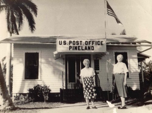 black and white photo of two women standing in-front of a building with the sign US Post Office Pineland 