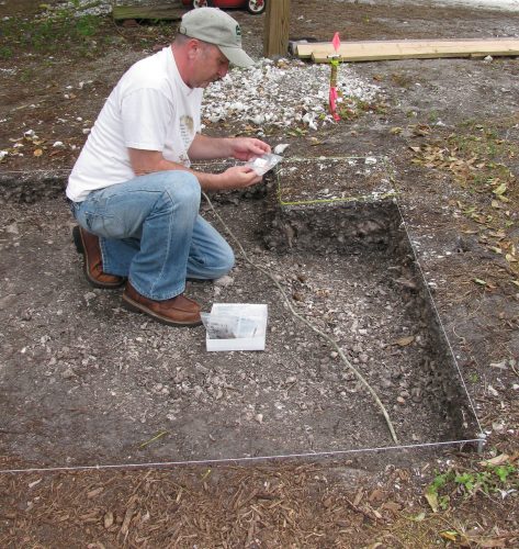 person kneeling in shallow archeological pit