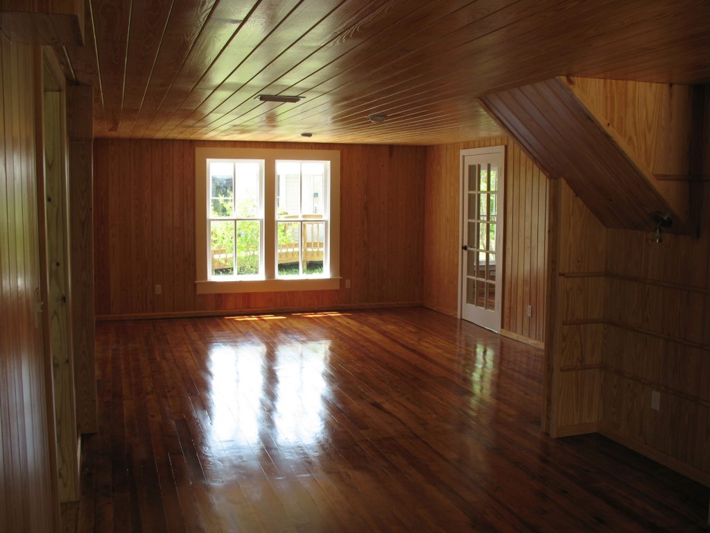 Empty room with pine wood floor wall and ceiling. The wood is highly polished and reflective