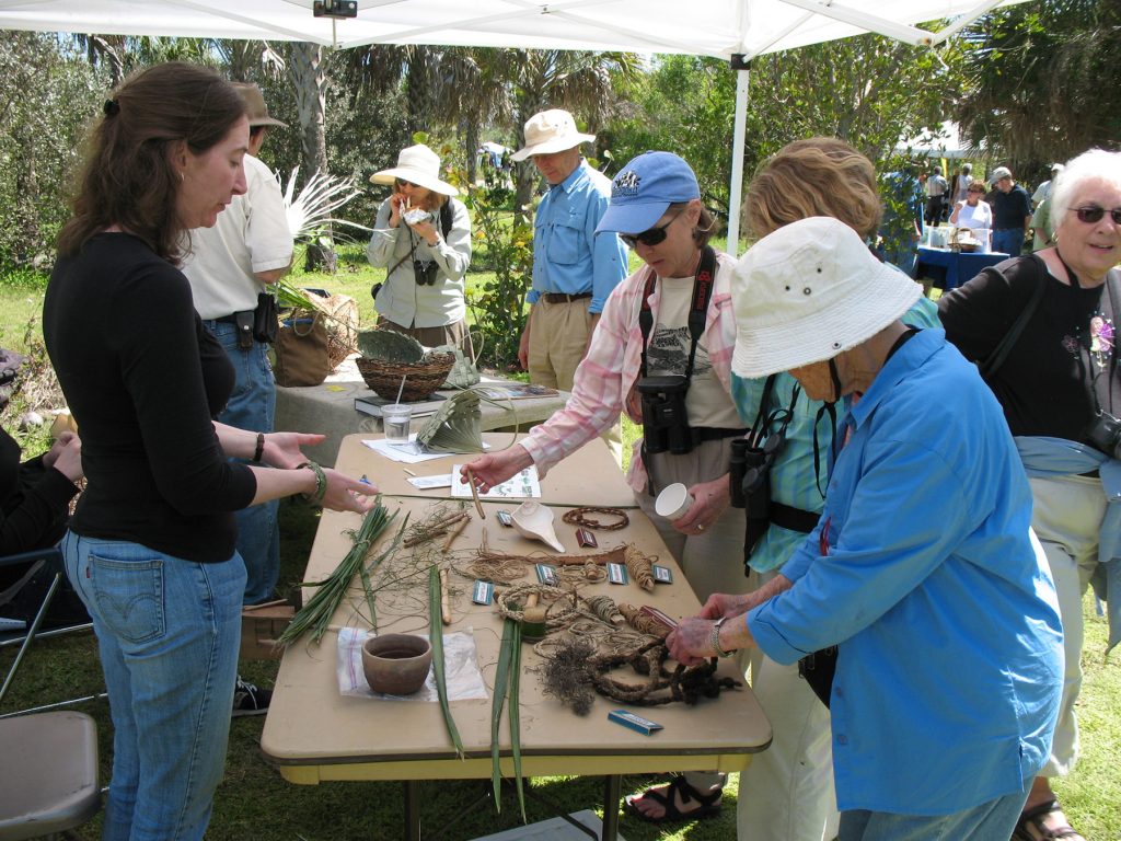 people stadn around a table and look at ropes and nets made from native plant fibers.
