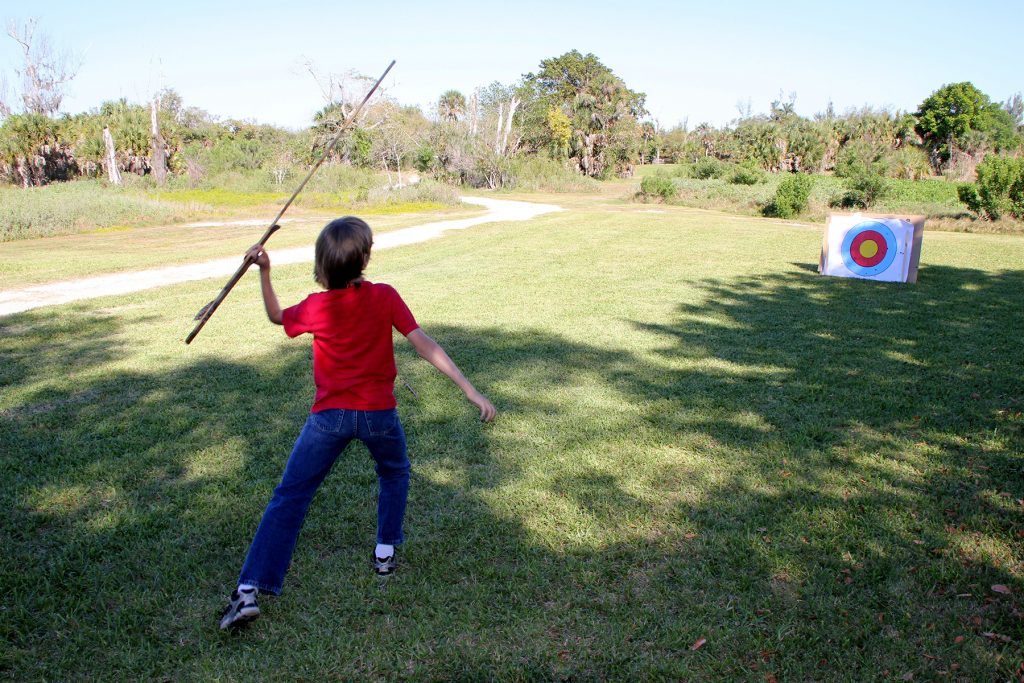 child throwing a spear at an target