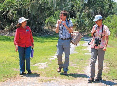 Cindy Bear, Marc Frank, and Laura Coglan walk along a dirt road discussing the challenges of managing native habitats.