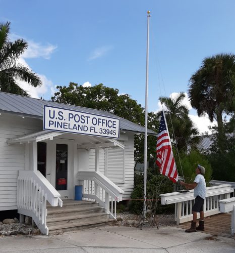 Andy Jendrusiak, RRC Groundskeeper, raises the flag outside the Pineland Post Office.