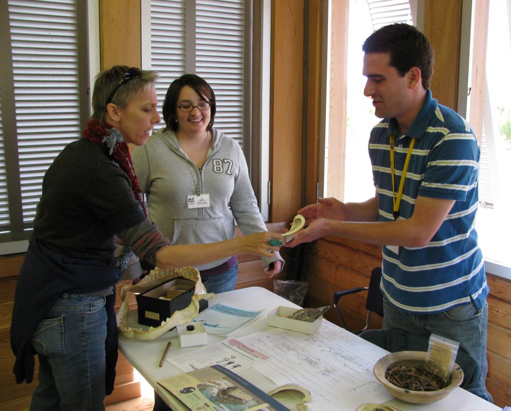 researcher holds a clam shell and speaks with visitors