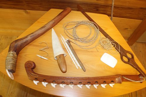 several tools made of wood, bone and robe displayed on a wooden table