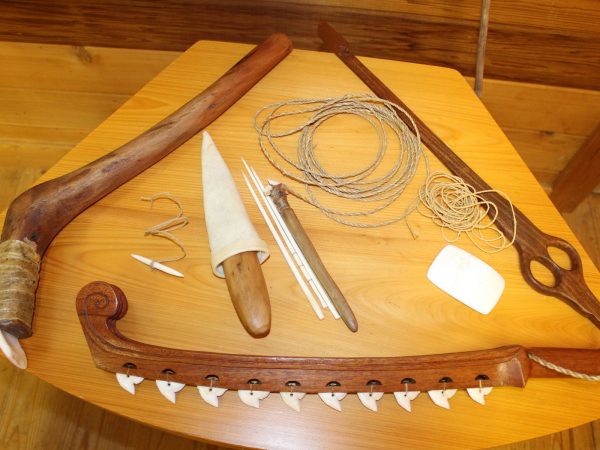 several tools made of wood, bone and robe displayed on a wooden table