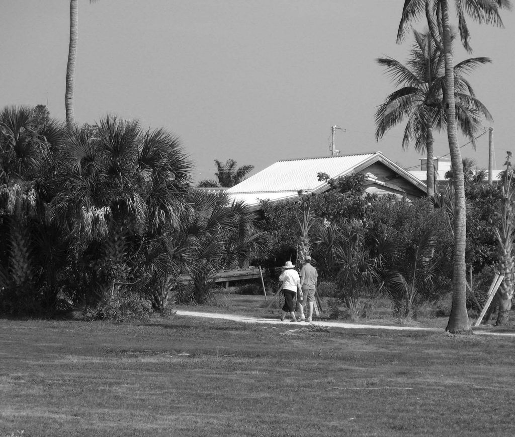 two people walk along a path towards a building