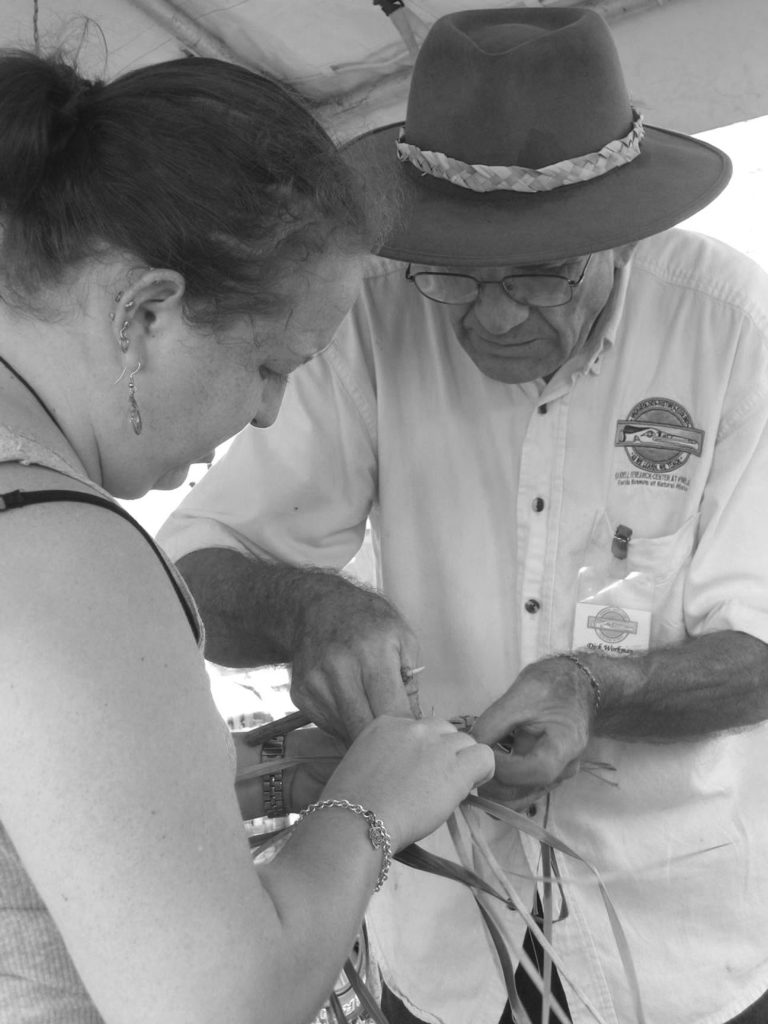 two people work on braiding palm fronds