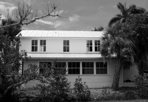 black and white photo of a two story house with many windows.