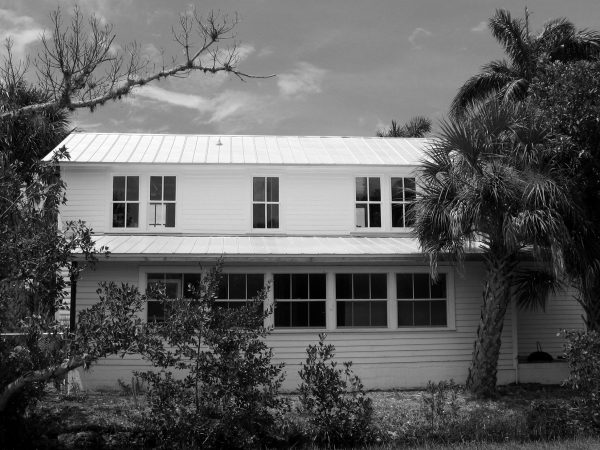 black and white photo of a two story house with many windows.