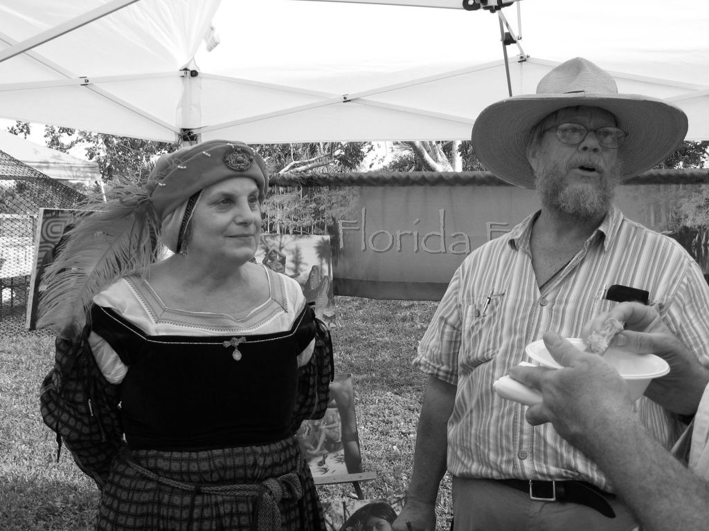 two people, one in costume, speak with visitors