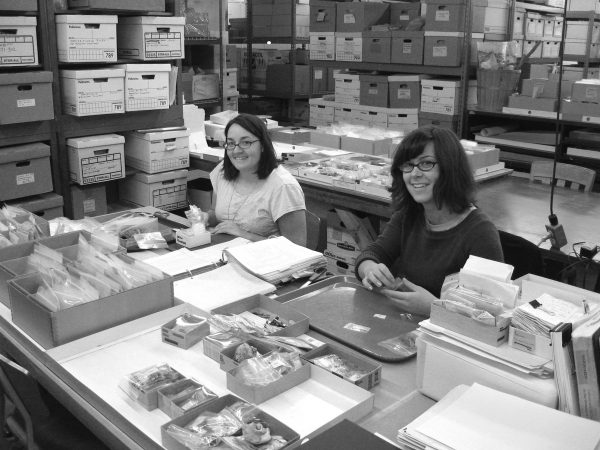 two researchers sit at a table filled with artifacts