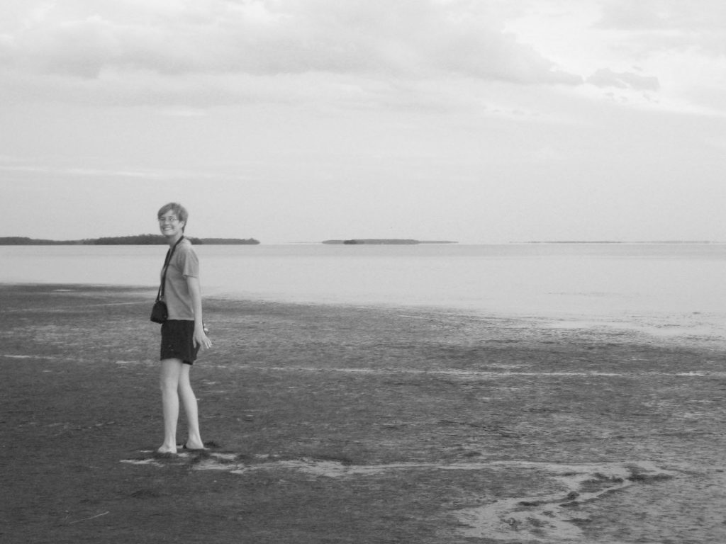 woman standing on mudflats next to the water