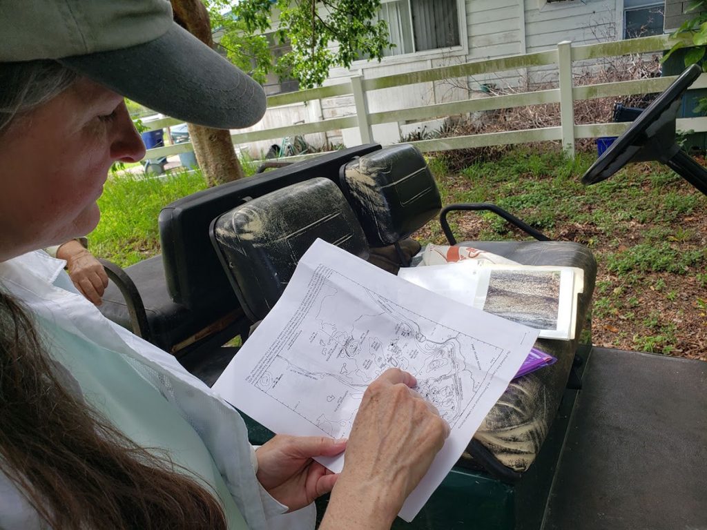 Karen Walker holds a paper map of the Randell Research Center and points at a spot on the map.