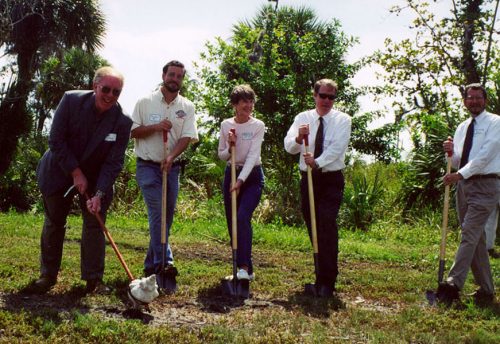 five people standing in a row with shovels for grown breaking ceremony