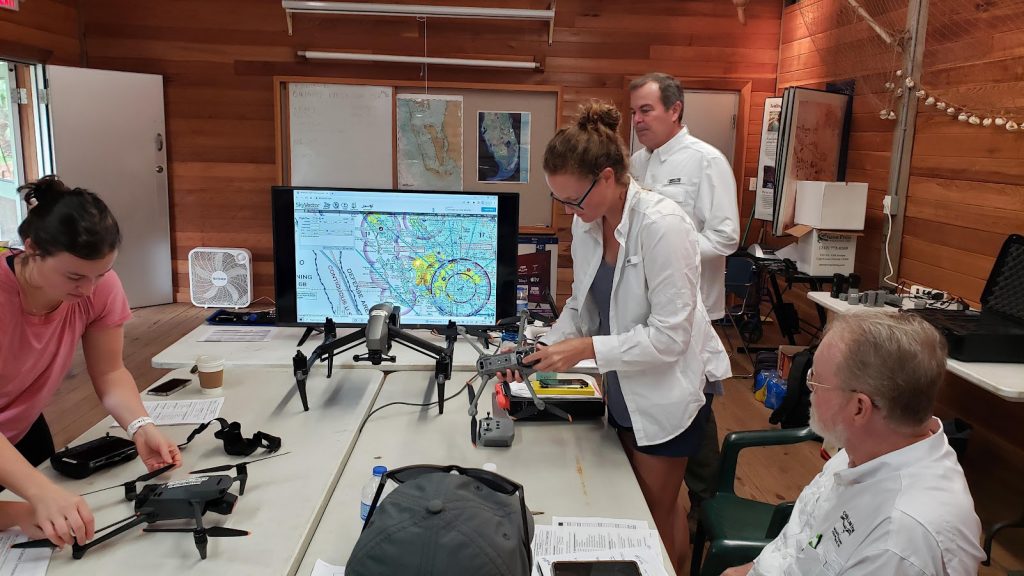 four people around a several tables holding drones and other equipment