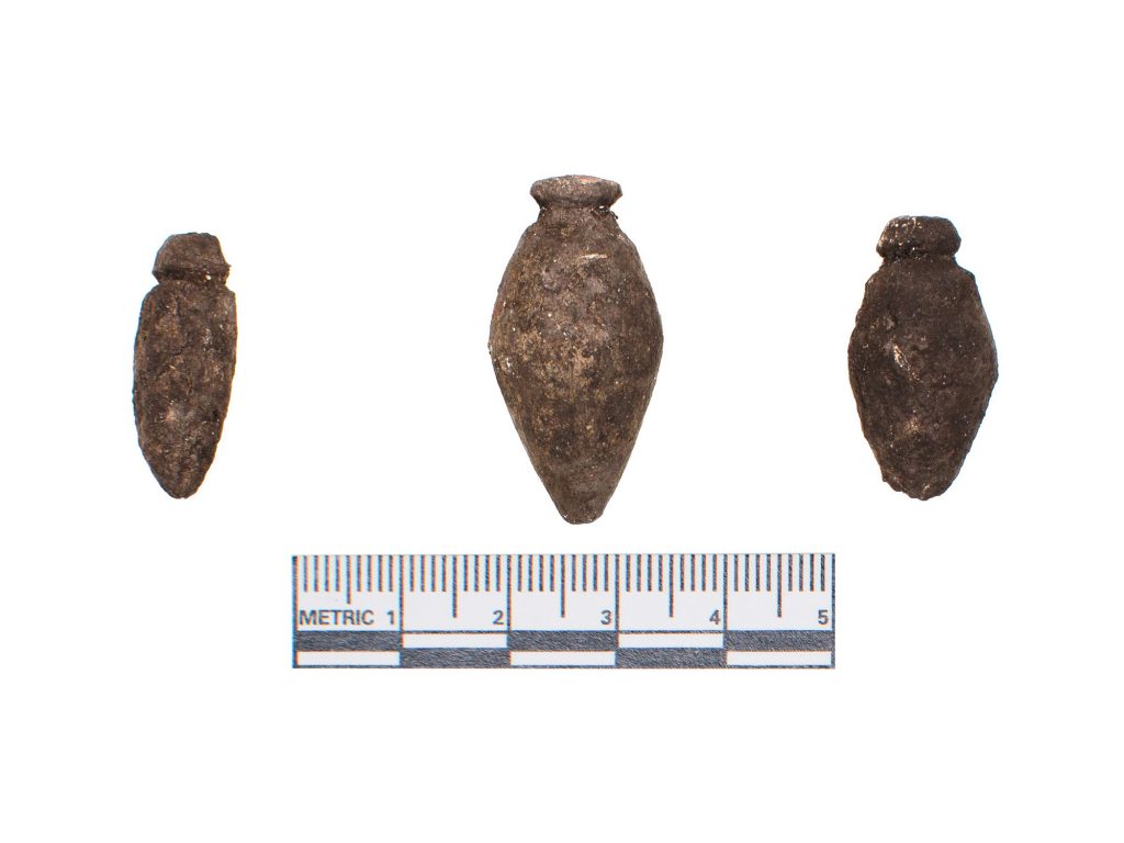 three metal plummets next to a ruler 