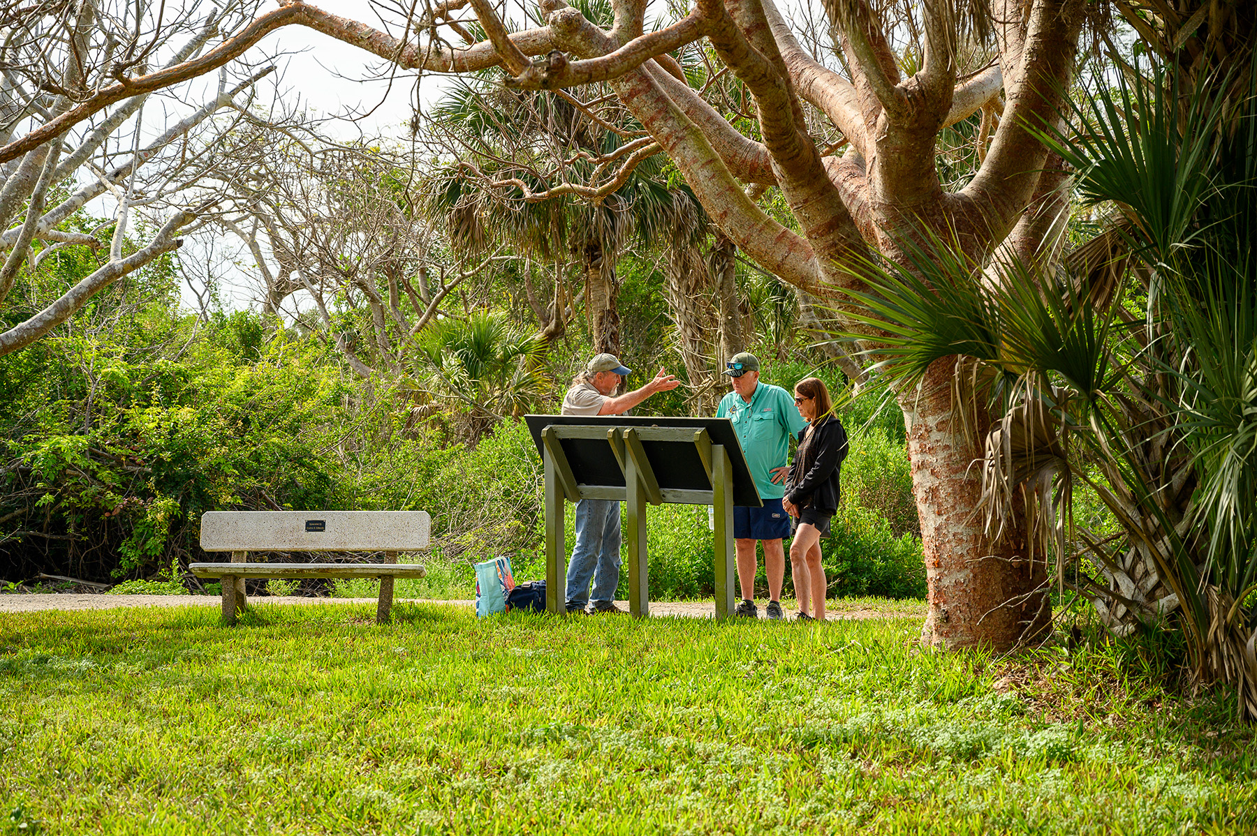 RRC volunteer speaking with visitors while standing next to one of the display information panels along the Calusa Heritage Trail at RRC.