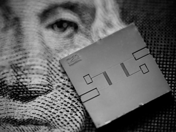 macro photo of small device on paper money for scale