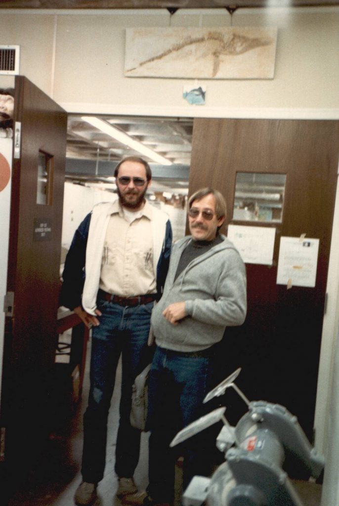 Art Poyer (left, collections manager from 1985-2020) and Russell McCarty (right) posing in front of the prep lab doors in Vertebrate Paleontology collection