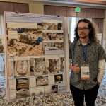 Student standing in front of poster presentation at conference