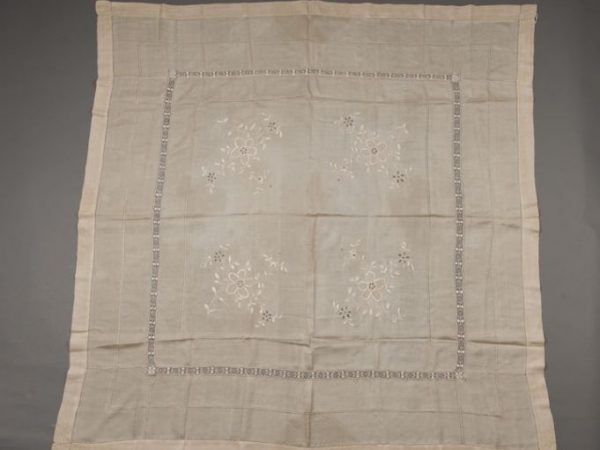 Table cloth dating back to the 1920s - 1930s of tussah silk (Antheraea pernyi) composed of natural color silk that was hand reeled and handwoven. It was embroidered by hand in floral motifs with mulberry silk (Bombyx mori). This is an example of “mission embroidery” produced in northeastern China between 1911 and 1949. See article entitled Mission Embroidery in China by Sigrid Reddy Watson, 1996, in PieceWork vol. 2 no. 2 pg. 49 -50. The open zones are a leno weave structure. Called pongee silk in USA and UK in early 20th century. Measures127 cm x 127 cm.