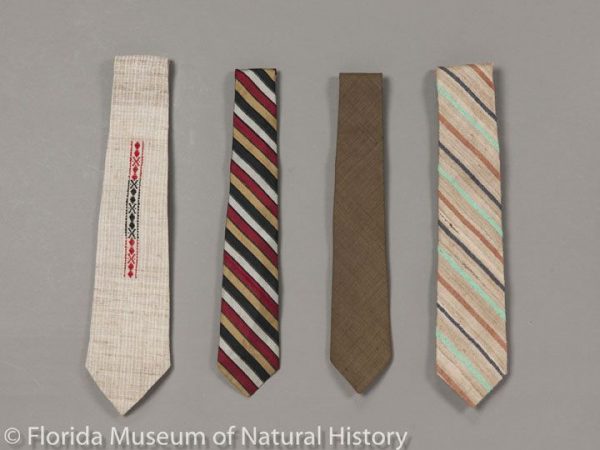 The first necktie, to the far left, is a necktie of natural colored eri silk (Samia ricini) and white cotton from Nagaland, India. The fabric is handwoven, and the embroidery is a traditional Naga design. Second necktie is a 1960s mulberry silk (Bombyx mori). It is from the department store in Oregon, Meier & Frank. The third necktie is made of tropical tasar silk (Antherea paphia = A. mylitta) and is believed to be made in the 1960s-1970s. Lastly, a RoosterⓇ brand necktie from the 1970s. This necktie is made of natural colored tropical tasar silk (Antherea paphia= A. mylitta) with diagonal bands of dyed mulberry silk.