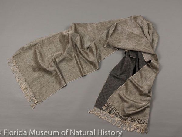 Brocaded shawl that is a blend of muga silk (Antheraea assamensis) and pashmina (goat wool), made in India and imported by Yves Delorme, a designer of fine linens in Paris. The fringes are hand-knotted, and the silk is the natural golden color of muga. The diamond pattern is one example of nightingale’s eye, which exists in several forms. Measures 76 cm X 193 cm