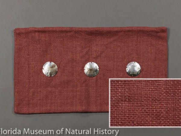 Cushion cover composed of tropical tasar silk (Antheraea paphia= A. mylitta). Handspun yarns and handwoven by a women’s livelihoood project in rural India working toward sustainability by harvesting the tasar cocoons as a renewable resource. The silk was hand dyed and the buttons are carved capiz shells (Placuna placenta). Meausres 30 cm X 54 cm