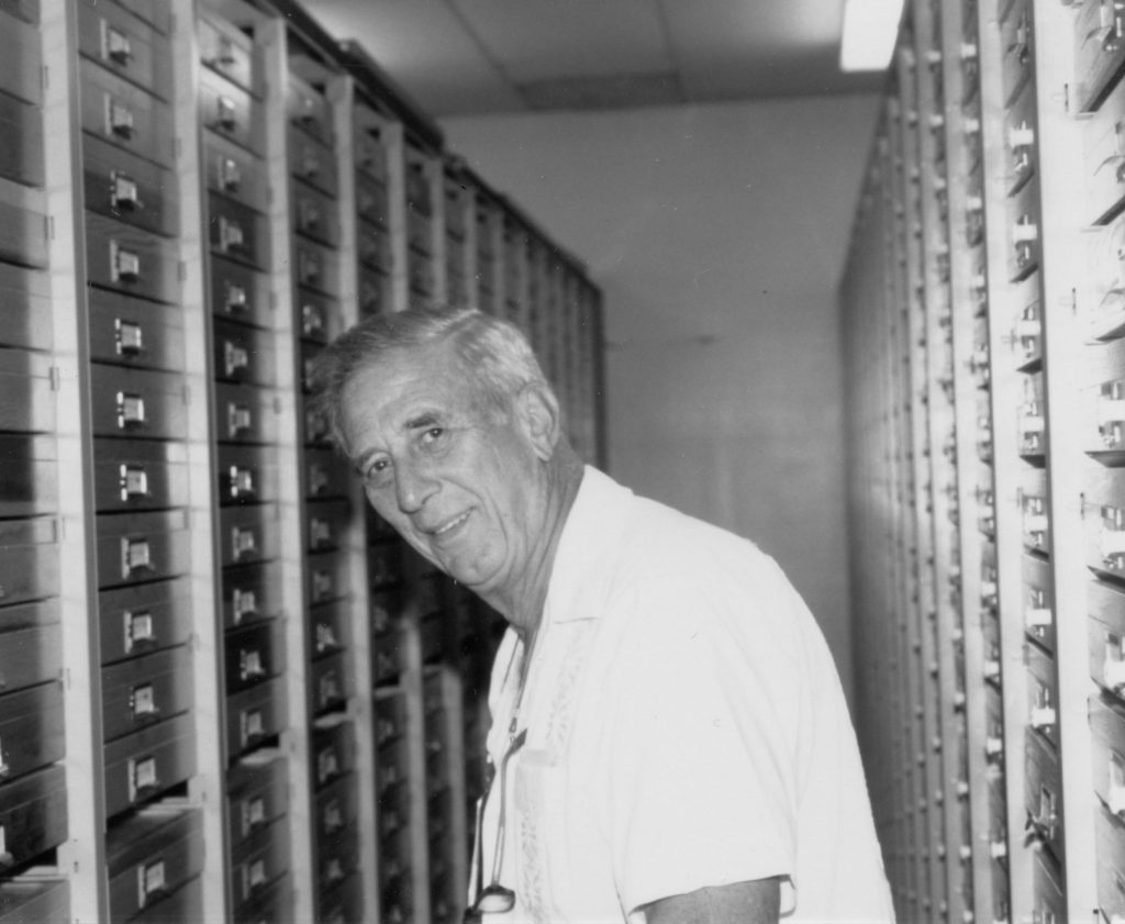 Picture of a man next to rows of insect drawers.