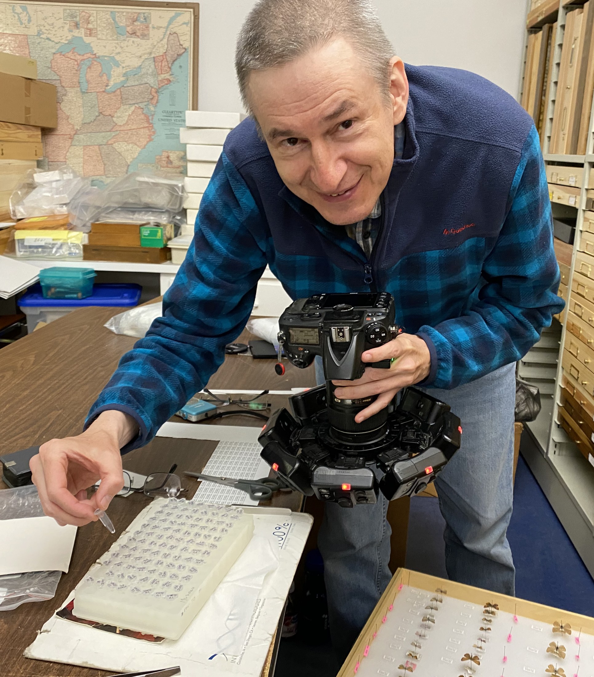 Picture of a man holding a camera and a small vial.