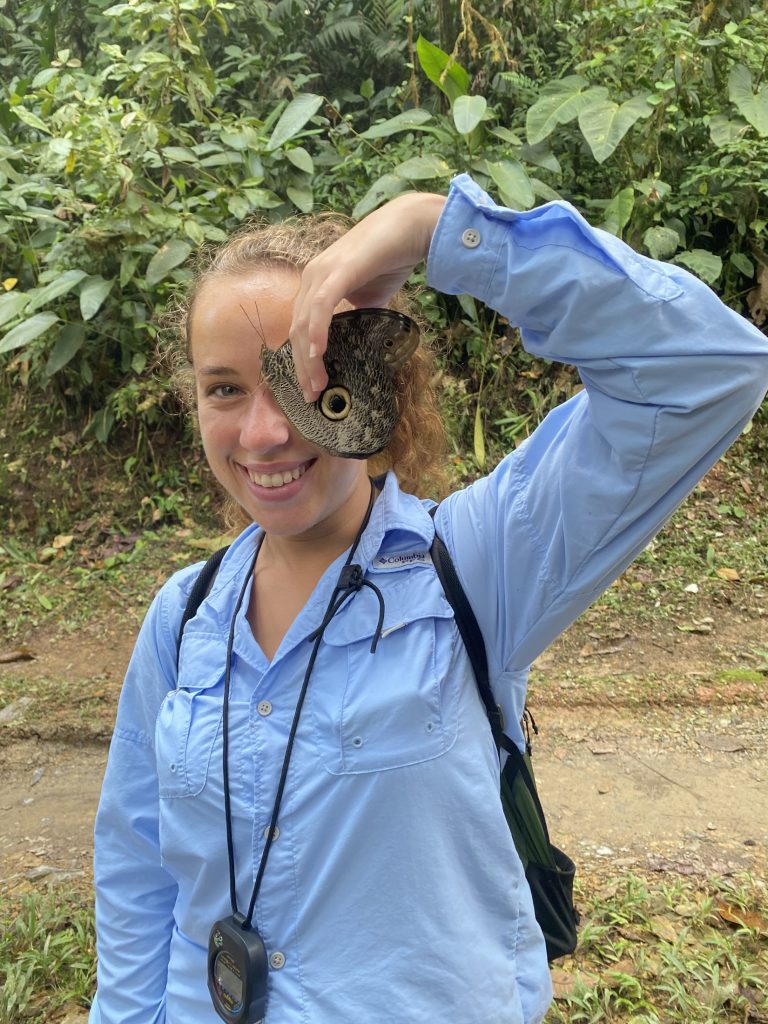 Picture of a woman holding an owl butterfly in front of her face.