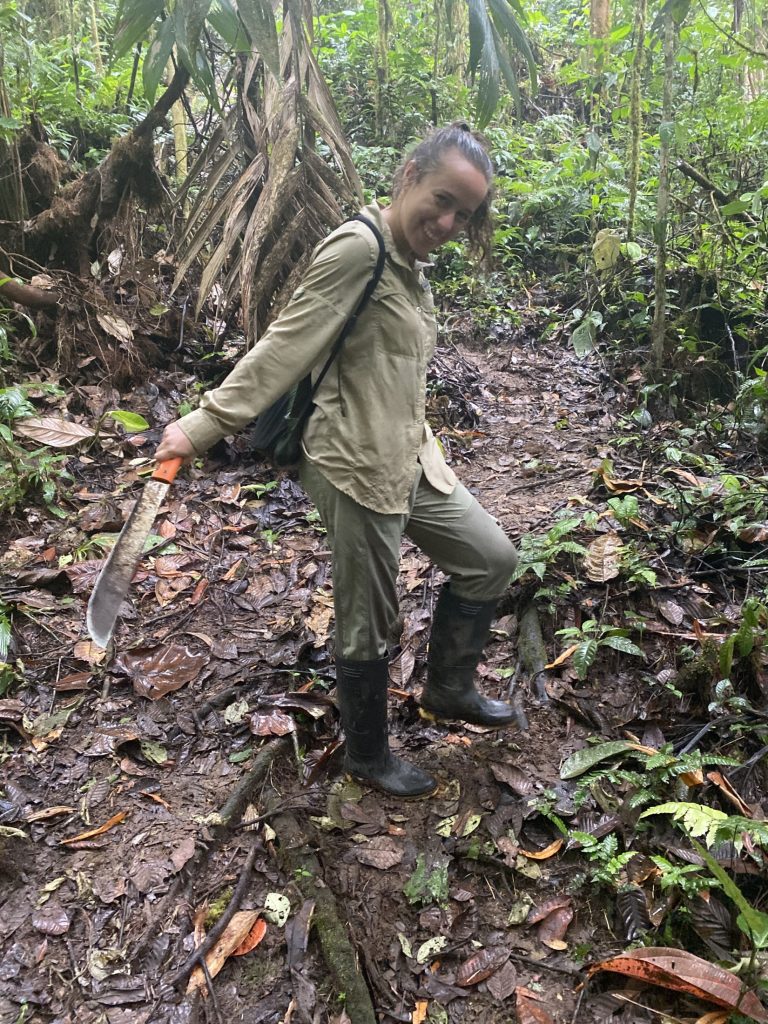Picture of a woman in a tropical forest holding a machete.