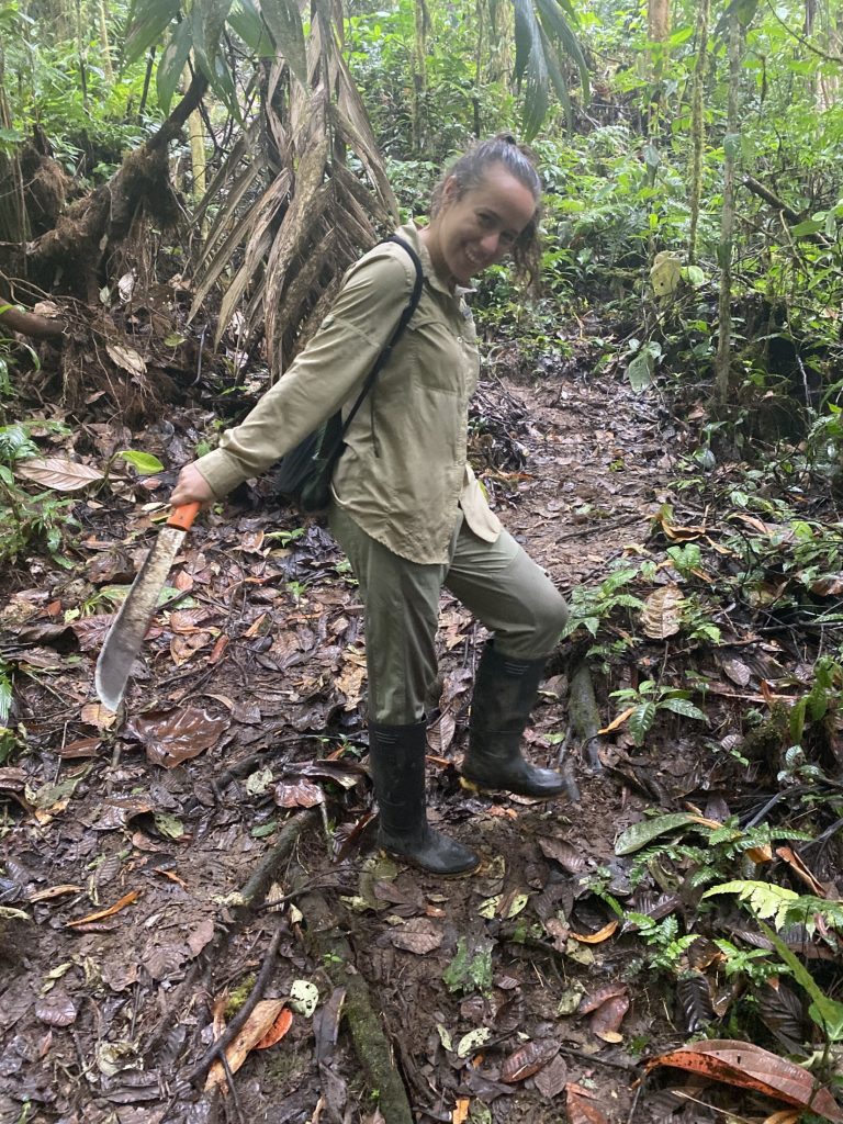 Picture of a woman in a tropical forest holding a machete.