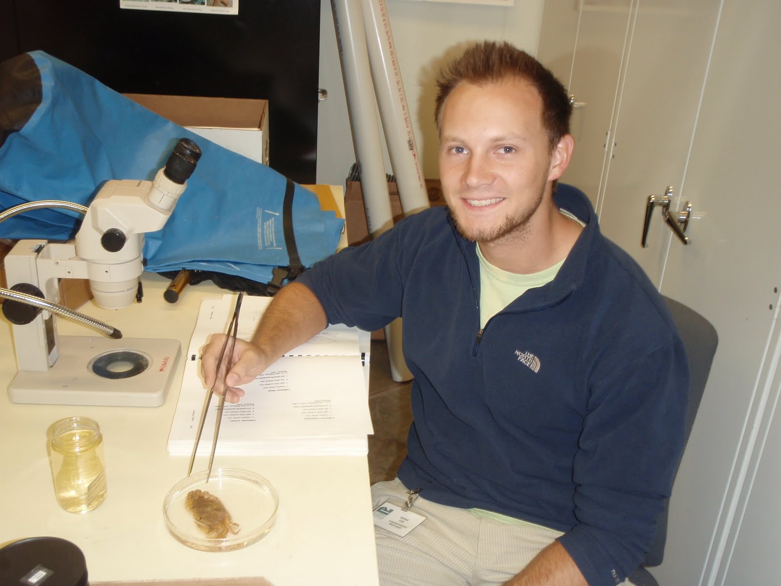 Derek with forceps and a crab in a petri dish