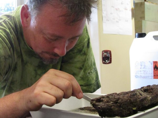 John picking at a rock with some forceps