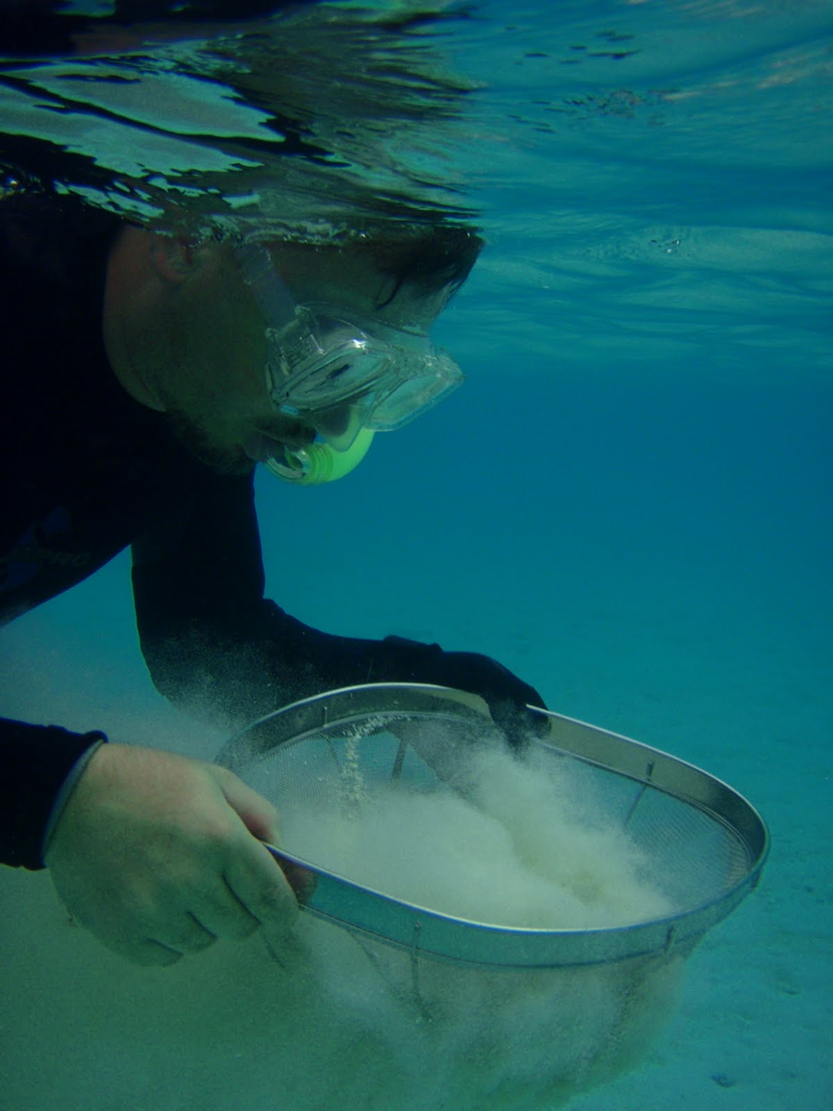 close up of John sieving sand while snorkeling on the surface